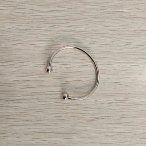 Close-up of a silver-toned titanium steel open cuff bracelet featuring smooth ball end details.