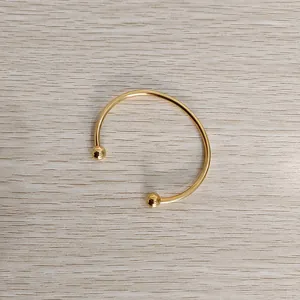 Detailed view of a gold titanium steel open cuff bracelet with screwable ball ends