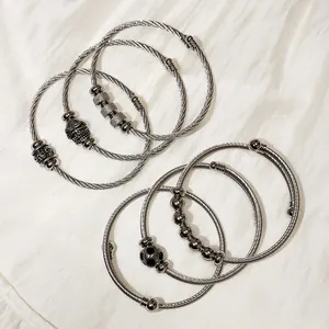 Detail shot of various stainless steel cable wire bracelets with skull and football charms