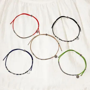 Détail de cinq bracelets en cordon réglables colorés avec perles et étiquettes en acier