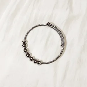 Detailed macro view of a flexible stainless steel twisted wire cuff bracelet with beads