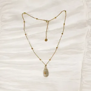 Primer plano del collar de acero inoxidable dorado con colgante de caracola natural