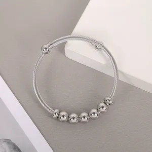 Macro view of a silver stainless steel wire cuff bracelet with polished beads.