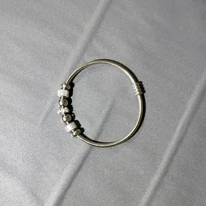 Detalle de pulsera de resorte de acero inoxidable con cuentas plateadas y cierre imán.