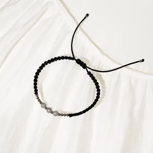 Primo piano di bracciale in cordino intrecciato nero con perle d'argento testurizzate
