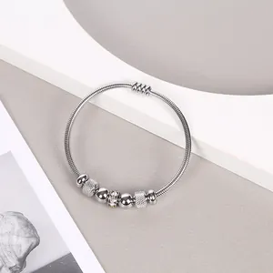 Elegante brazalete de acero inoxidable plateado con muelle, cuentas texturizadas y cristales