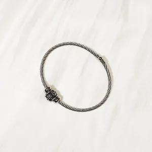 Macro view of a durable stainless steel cable bracelet with a unique skull charm detail.