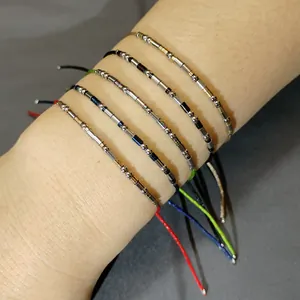Vue détaillée de bracelets réglables en cordon de couleur avec perles en acier inox.