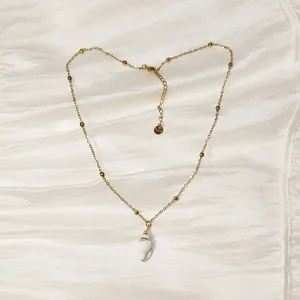 Detalle del collar de acero inoxidable con colgante de caracola blanca de estilo océano