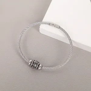 Close-up of a stainless steel wire bracelet featuring a detailed skull charm detail