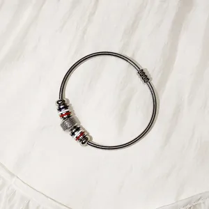 Primer plano de brazalete de acero inoxidable con cuentas decorativas a rayas