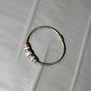 Vista detallada de un brazalete de resorte de acero inoxidable con cuentas tricolores y cierre magnético.