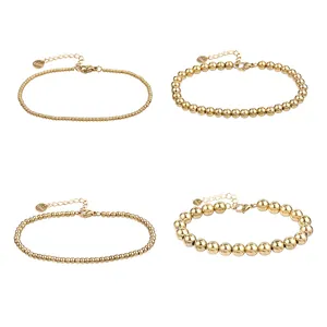 Dettaglio di quattro bracciali a sfere in acciaio inossidabile dorato di varie dimensioni