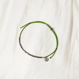 Vue détaillée du bracelet en corde tissée verte avec perles et tubes en acier inoxydable