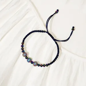 Dettaglio del bracciale in corda intrecciata con perline iridescenti in acciaio inossidabile