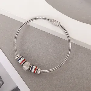 Detalle de brazalete de acero inoxidable con cuentas esmaltadas en rojo, blanco y azul