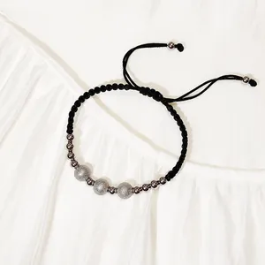 Vista dettagliata di un bracciale a corda intrecciata nera con perle d'argento satinate