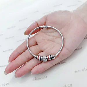 Primer plano de brazalete de acero inoxidable con cierre magnético y abalorios.