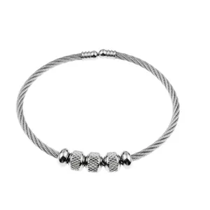 Detailed view of women's silver stainless steel wire bangle with textured charms
