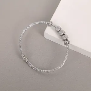 Macro detail of a silver stainless steel twisted cable bracelet with textured metallic beads