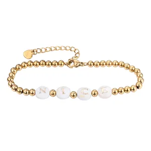 Detailansicht eines Goldperlenarmbands mit weißen Muschelscheiben und 'NICE' Briefen