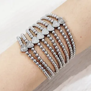 Close-up of stacked stainless steel bead elastic bracelets with heart letter charms