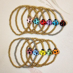 Detailed view of colorful ceramic ladybug charms on gold and silver beaded elastic bracelets.