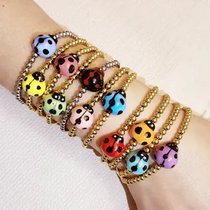 Close-up of colorful ceramic ladybug charms on gold and silver beaded elastic bracelets