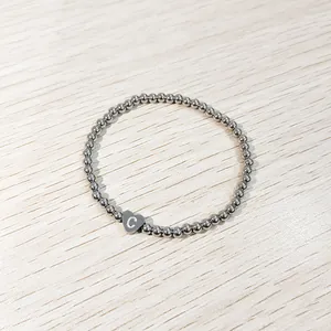 Close-up view of silver stainless steel beaded elastic bracelet with heart letter C charm