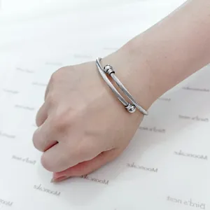 Close-up detail of a silver stainless steel cable wire cuff bracelet on a female wrist