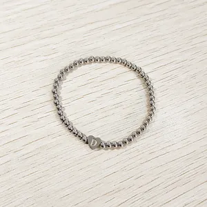 Close-up of heart charm on silver stainless steel beaded elastic bracelet with letter D