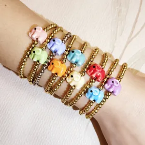 Detailed shot of multiple colorful ceramic elephant charms on gold bead bracelets