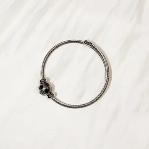 Detailed macro shot of a stainless steel twisted wire bangle with a soccer ball bead.