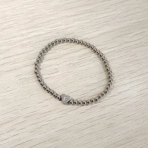 Detailed view of a silver stainless steel bead bracelet with an engraved heart 'F' charm