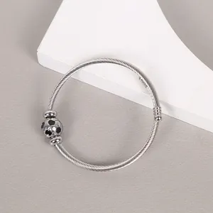 Detail of durable stainless steel wire bangle featuring a soccer ball charm design