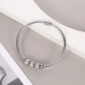 Pulsera de resorte de acero inoxidable plateado en un soporte estético curvo blanco