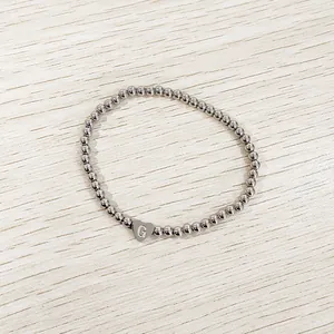 Detail of silver stainless steel bead bracelet featuring an engraved heart 'G' charm.
