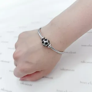 Detailed view of a stainless steel wire bracelet featuring a soccer ball charm on a wrist