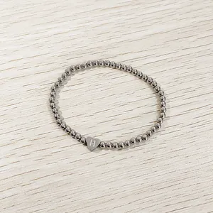 Close-up of a silver stainless steel beaded elastic bracelet with letter H heart charm.