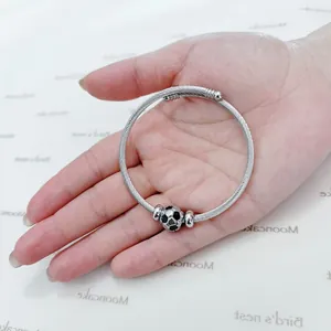 Detailed view of silver stainless steel twisted cable bangle with a soccer ball charm