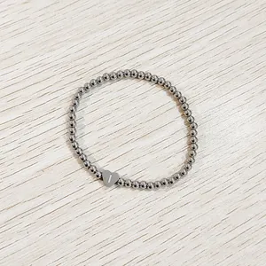 Close-up detail of a stainless steel bead bracelet with an engraved heart initial charm