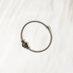 Detailed view of stainless steel cable bangle with a gothic skull charm decoration.
