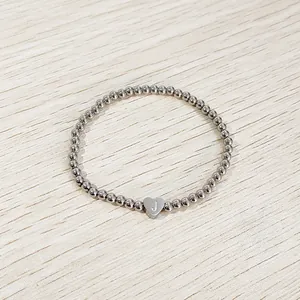 Macro view of a silver stainless steel beaded bracelet with heart charm and letter J