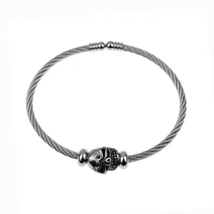 Detail of a punk style stainless steel wire bracelet featuring a metallic skull charm.