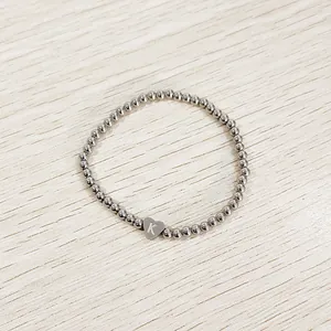 Close-up of stainless steel bead bracelet featuring a heart charm with letter K engraving