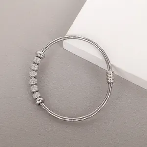 Detalle de un brazalete de resorte de acero inoxidable plateado para mujer, elegante.