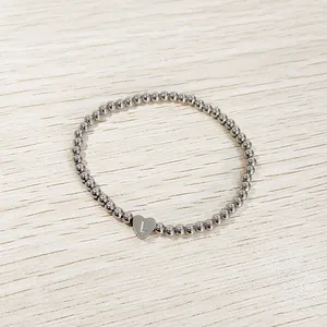 Detailed view of a silver stainless steel beaded elastic bracelet with a heart initial L charm