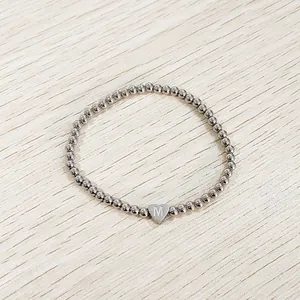 Detailed view of stainless steel beaded bracelet with an engraved heart charm.