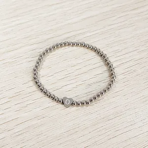 Close-up of a silver stainless steel beaded bracelet with a heart initial O charm.