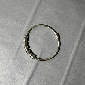 Primer plano detallado de una pulsera minimalista de resorte en acero inoxidable con cuentas